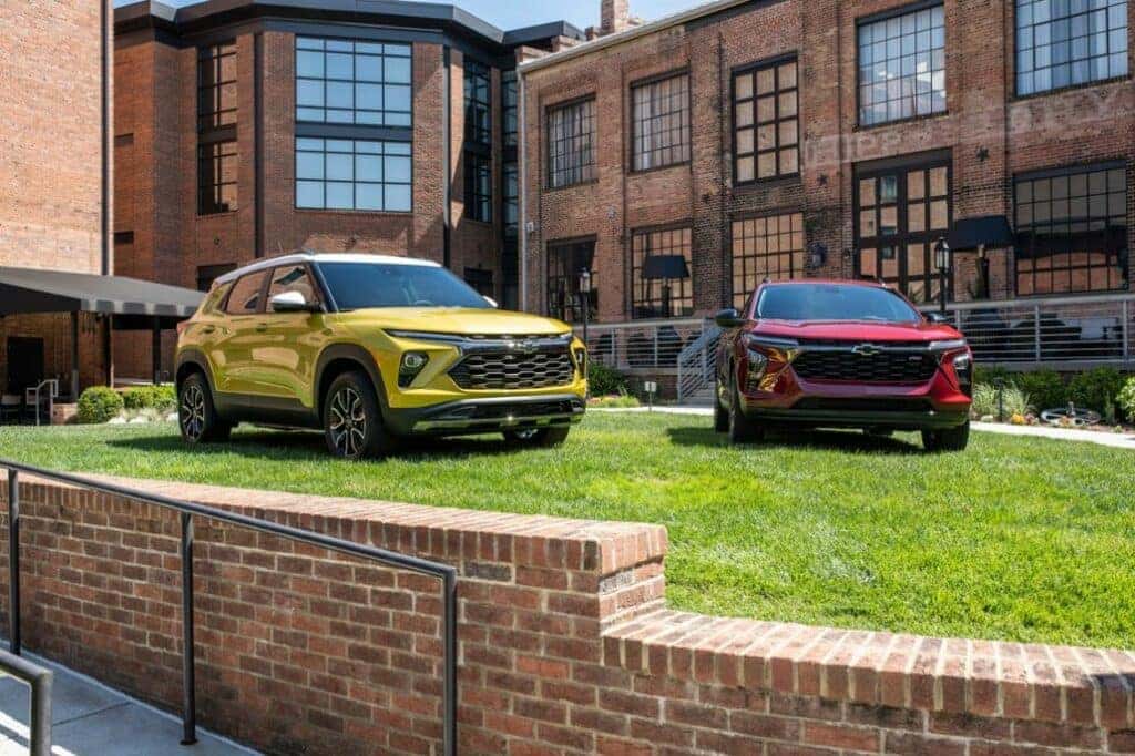 View of 2024 Chevrolet Trax RS in Crimson Red Metallic and 2024 Chevrolet Trailblazer LT in in Nitro Yellow Metallic staged in front of the Foundry Hotel Asheville.