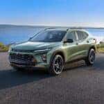 3/4 view of Chevrolet Trax ACTIV in Cacti Green parked on a road in front of a lake. Pre-production model shown. Actual production model may vary. Available in spring 2023. Cacti Green exterior color late availability.