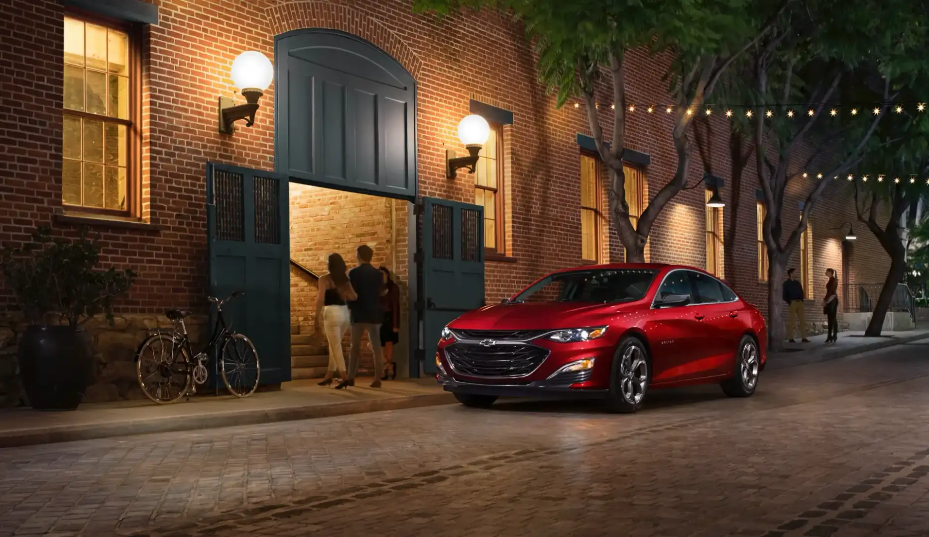 Red Chevrolet Malibu parked on a quaint street with lighting
