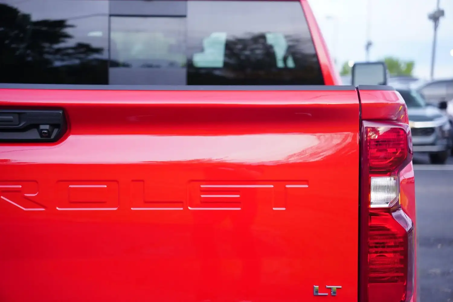 Close-up rear view of a red Chevrolet Silverado LT tailgate showing the stamped lettering and right taillight assembly
