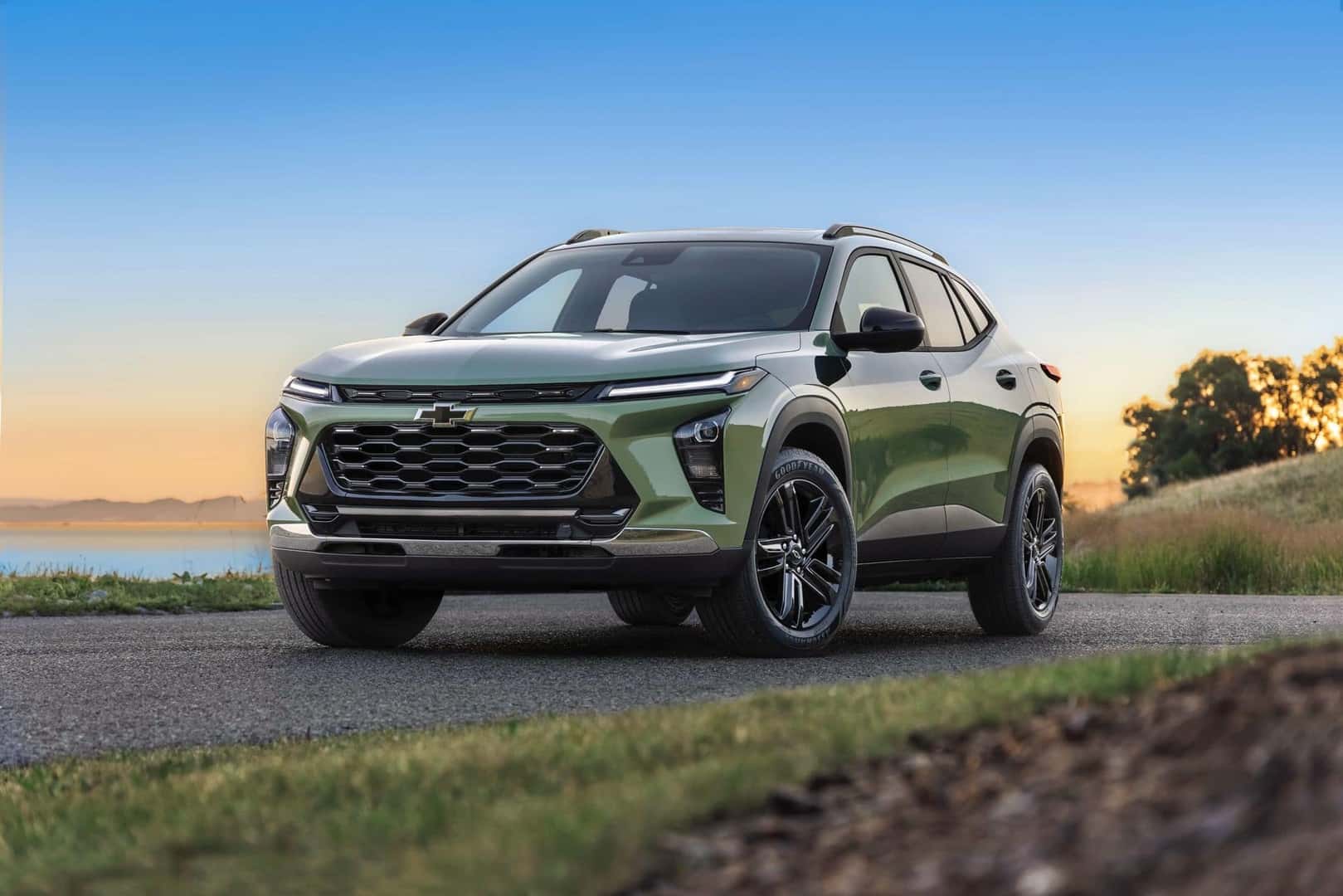 A Gorgeous Green 2026 Chevrolet Trax, Parked In Front Of A Gradient Yellow To Blue Sky