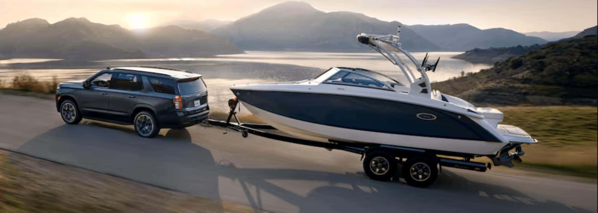 The Strong And Burly Chevrolet Tahoe Towing A Boat As The Sun Rises Over The Marvelous Mountains