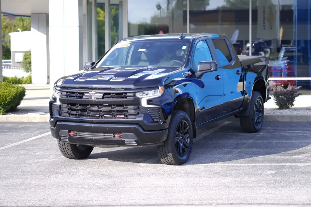 A front three-quarter view of a dark blue Chevrolet Silverado 1500 crew cab truck parked on a dealership lot, showcasing the black front grille, Z71 badging, and matching black wheels