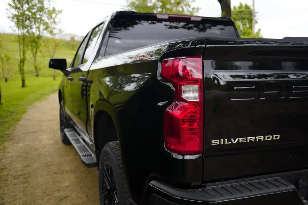 Rear corner view of a black Chevrolet Silverado Custom Trail Boss truck on a path, highlighting high-demand truck trade-ins at Barry's Chevrolet in West Union