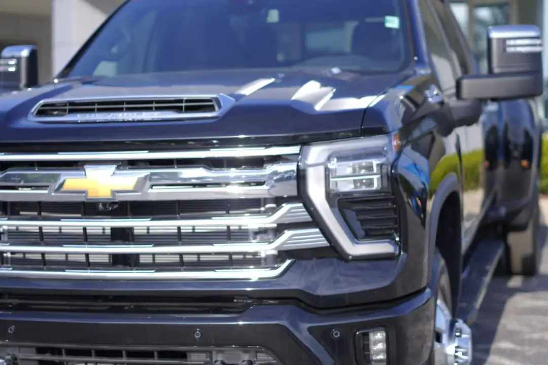 A front three-quarter view of a black Chevrolet Silverado 2500HD pickup truck on a dealership lot, highlighting its massive chrome grille and large towing mirrors.