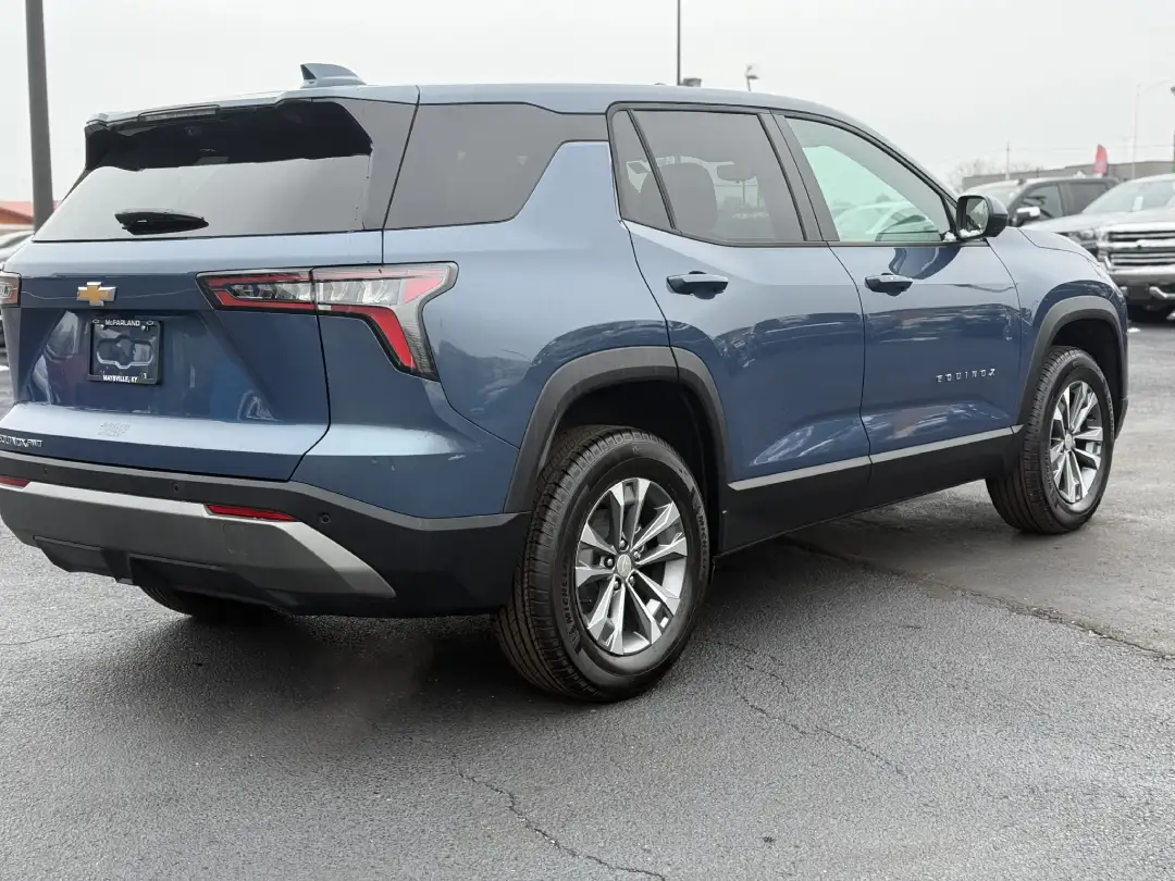 A rear three-quarter view of a metallic blue Chevrolet Equinox SUV parked on an asphalt dealership lot on an overcast day.