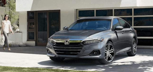 Certified Pre-owned Honda Accord parked in front of a garage in the driveway with a business woman walking towards it.