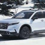 White Honda CR-V driving through snow with winter tires.