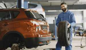 Service technician carrying tire in auto shop