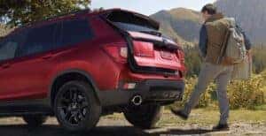 A man using the hands-free access power tailgate on a red 2024 Honda Passport