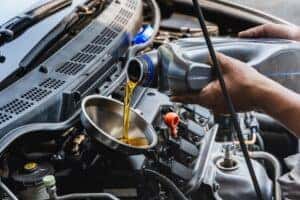 Car mechanic pouring engine oil into vehicle during oil change