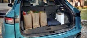 The open trunk of a teal 2024 Honda Prologue EV holding groceries parked in front of a home