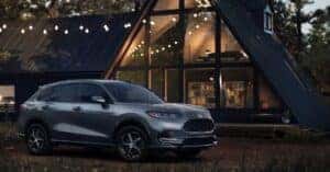 A 2025 Honda HR-V parked In the woods in front of a lit up cabin