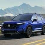 A blue 2025 Honda CR-V driving on the road through the mountains