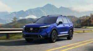 A blue 2025 Honda CR-V driving on the road through the mountains