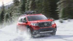 A red 2025 Honda Passport driving through the snow