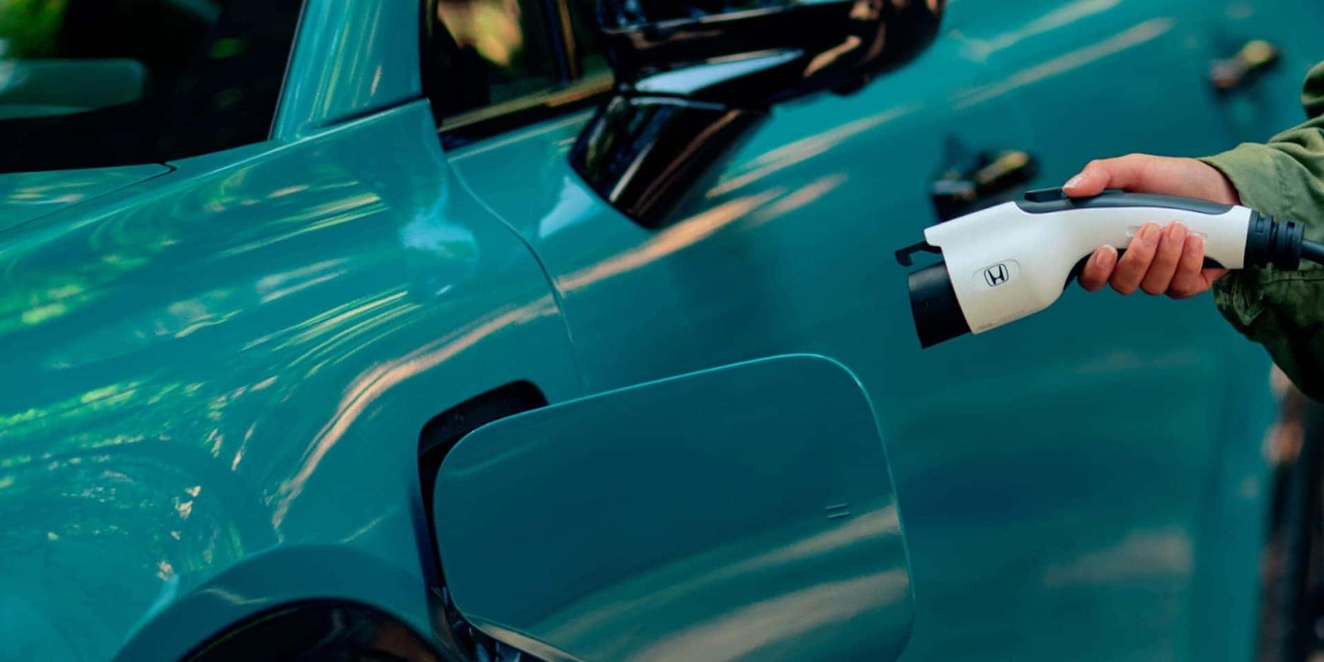 A close-up of a charger plugged into a teal 2026 Honda Prologue EV