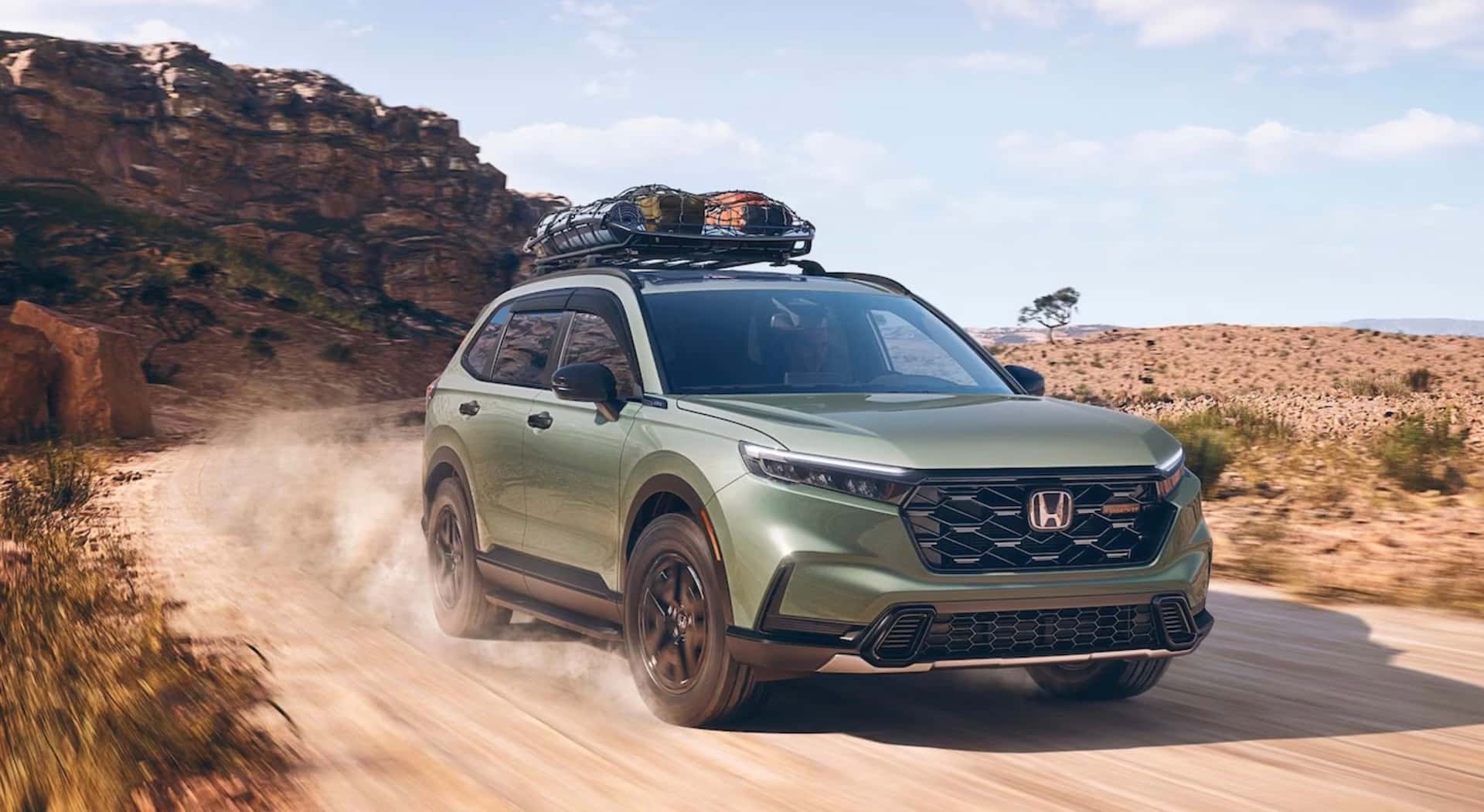 A green 2026 Honda CR-V TrailSport driving with a cargo net through the desert