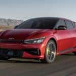 A Red 2023 Kia EV6 Crossover Driving On the Road Through the Desert