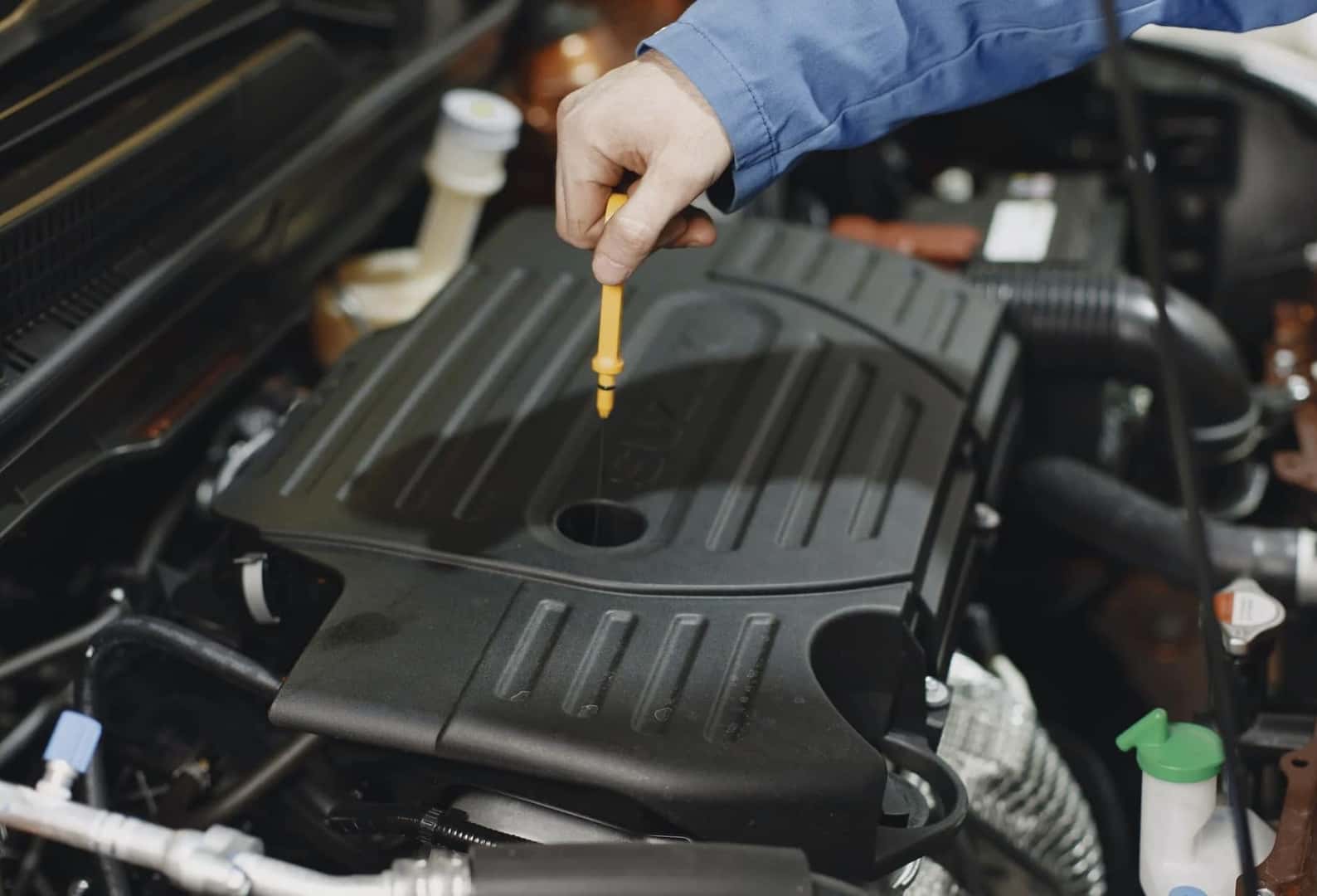A service technician testing the oil of a car during a routine oil change