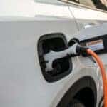 A white 2023 Kia Sorento Plug-in Hybrid vehicle plugged into a charging station