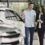 A man and a woman shopping in a car dealership
