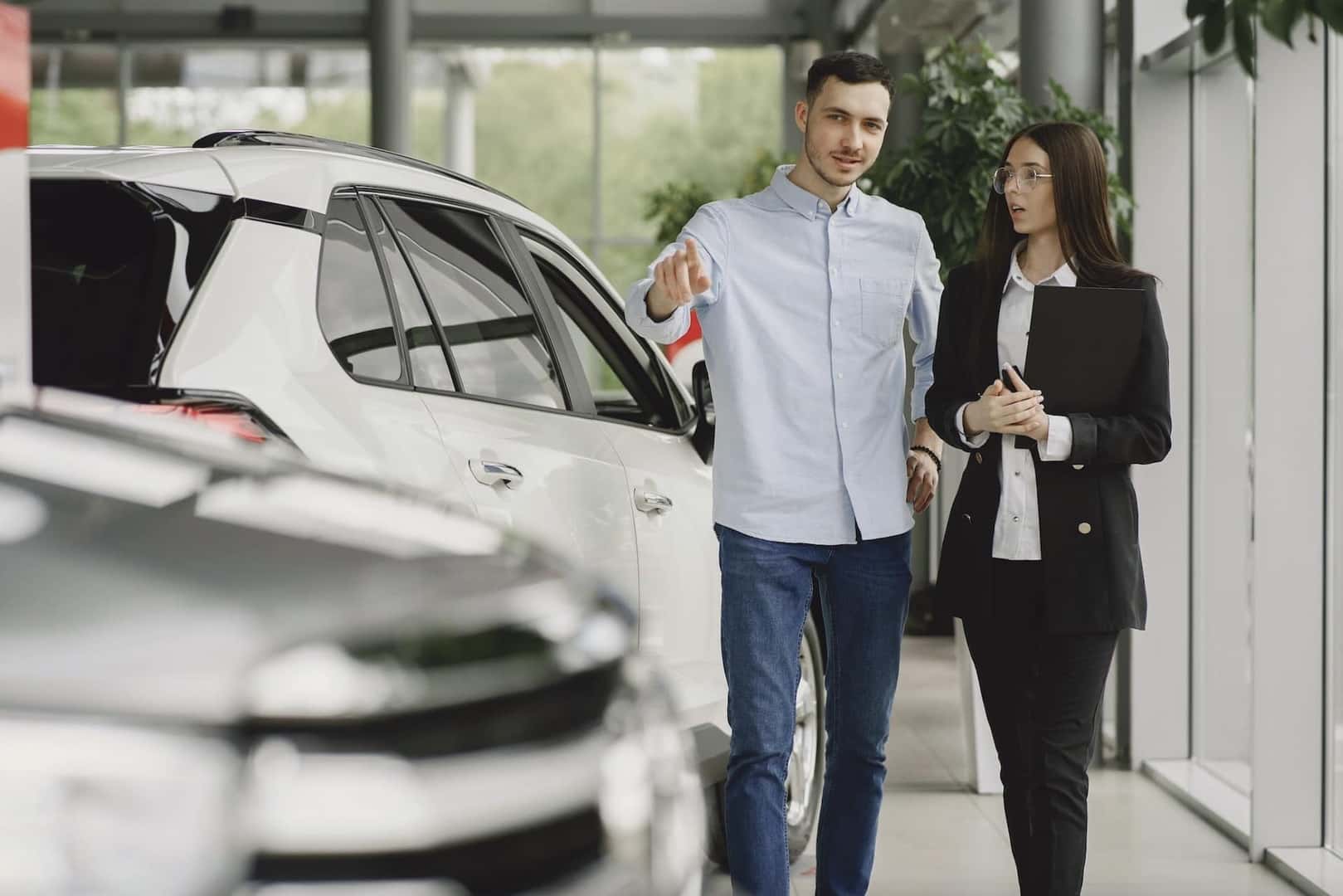 A man and a woman shopping in a car dealership