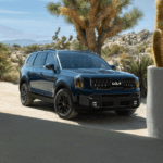 A dark blue 2024 Kia Telluride parked outside a home in the desert
