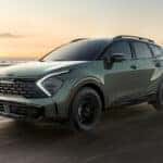 A green 2025 Kia Sportage SUV driving on the beach