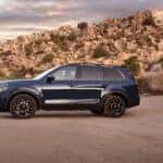 A blue 2024 Kia Telluride SUV parked next to a pile of rocks