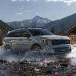 A gray 2025 Kia Sorento driving through the water in the mountains