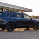 A black 2025 Kia Telluride SUV parked outside of a modern house in the desert
