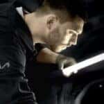 A Kia service technician using a light to look at an engine