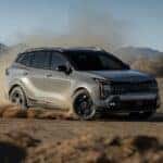 A gray 2026 Kia Sportage driving fast kicking up dirt