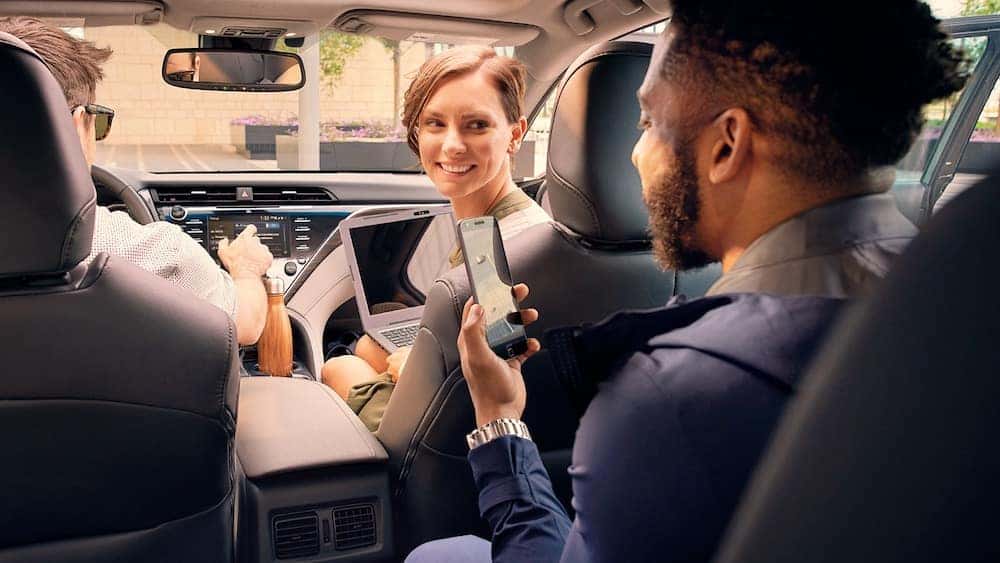 Toyota camry with man using smartphone in backseat