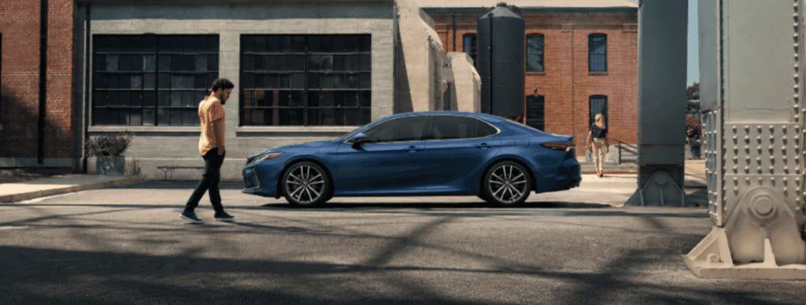 2026 Toyota Camry in blue parked on a city street with an urban backdrop
