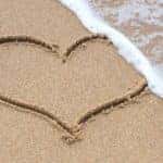 Beach with heart on it and wave approaching heart