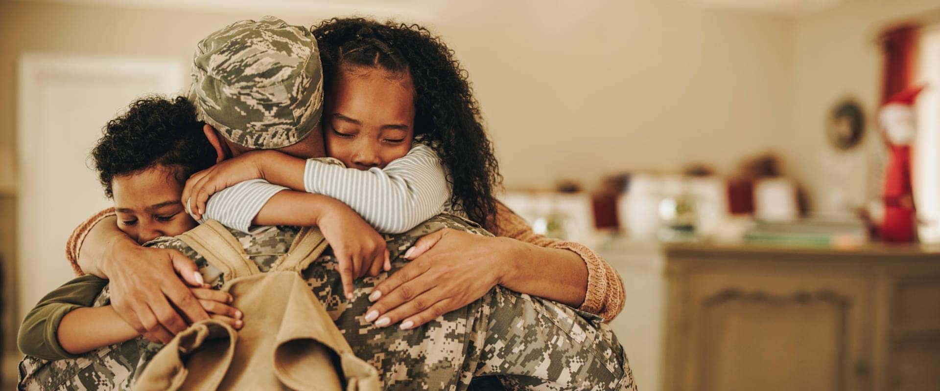 A soldier embraces his daughter and son, showcasing a heartfelt reunion filled with love and joy.