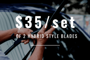 The background is photograph of a vehicle windshield. In front of the windshield are two hands of lighter skin color that are holding two wiper blades. On top of that it says "$35/set of 2 hybrid style blades" in white lettering. 
