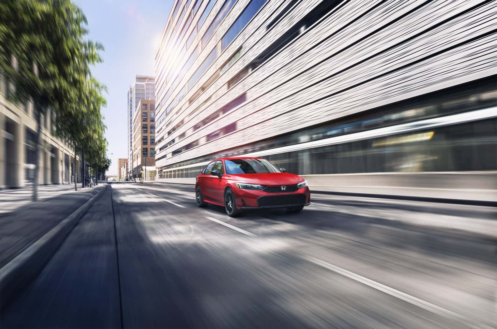 Red Honda Civic Sedan Sport driving along a city street