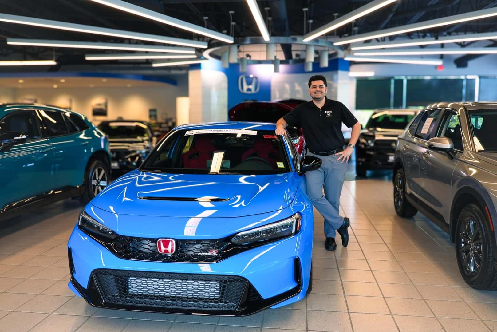 An Ide Honda sales team member beside a blue Honda Civic Type R in the showroom