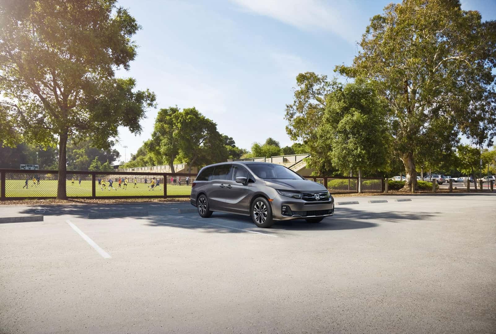 Gray Honda Odyssey parked beside a youth sports field