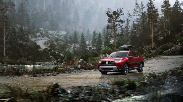 Red 2026 Honda Pilot Elite driving on a forest road