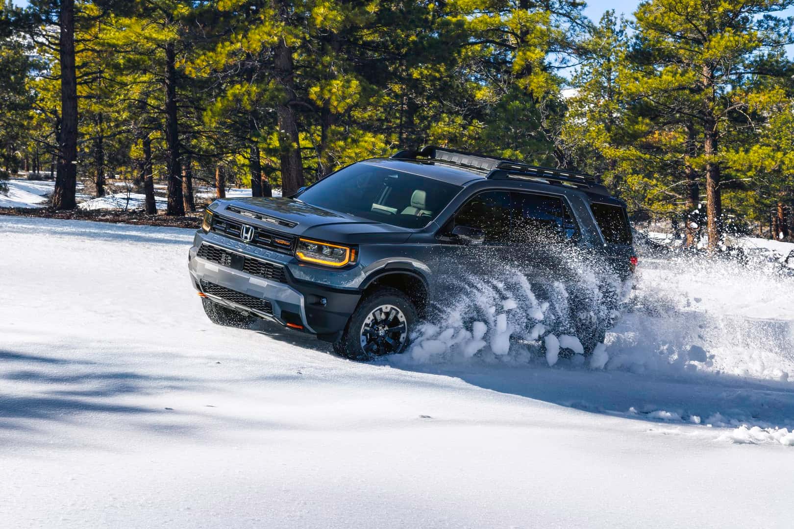 2027 Honda Passport TrailSport Elite driving through snow in a wooded setting