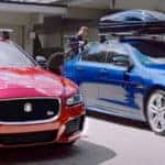 Two men securing canoes on roof racks on their Jaguar XE models