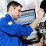 Auto mechanic at wheel alignment work with spanner