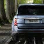 Back view of a gray Range Rover driving through a forested trail