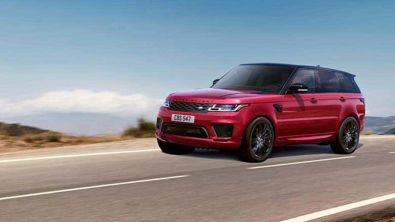 Red Range Rover Sport driving on a highway with a clear blue sky in the background