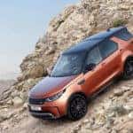 Orange Land Rover Discovery driving down a steep, rocky mountain