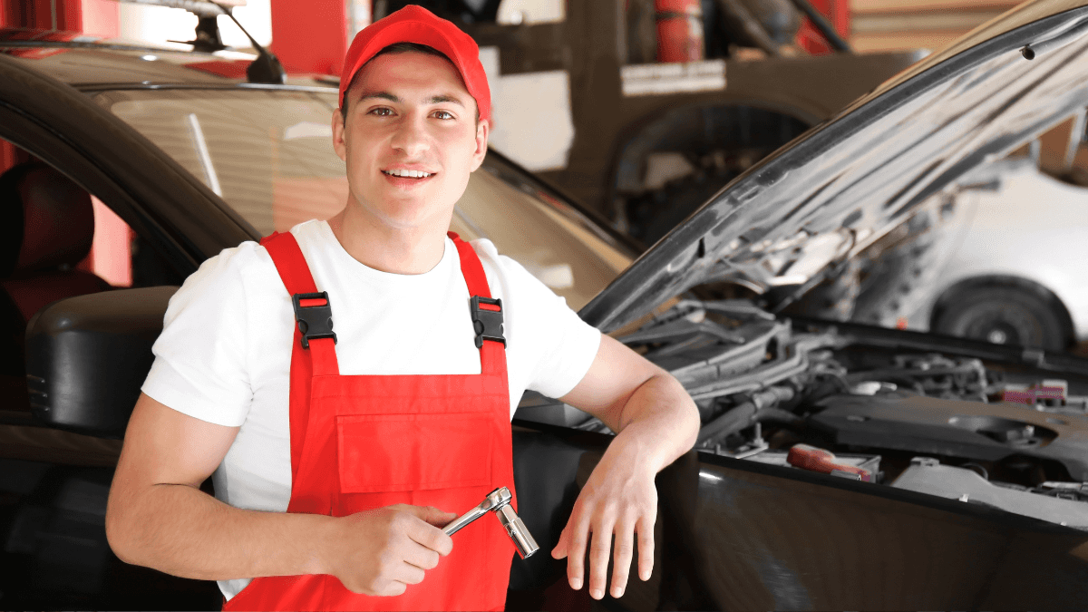A service technician leaning against a car with a popped hood